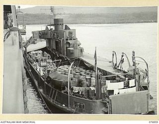 JACQUINOT BAY, NEW BRITAIN. 1944-11-07. THE FRANCES PEAT AN EX HAWKESBURY RIVER, NEW SOUTH WALES VEHICULAR FERRY TAKING ON DRUMS OF PETROL AND OIL FROM THE AMERICAN TROOPSHIP CAPE ALEXANDER