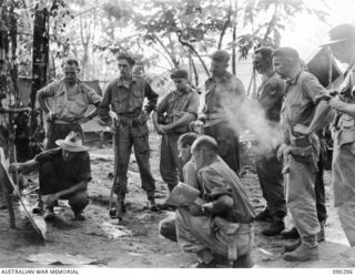 Lieutenant Colonel J G McKinna, Commanding Officer 25th Infantry Battalion (squatting on left), outlining positions on a map to 2/4th Armoured Regiment Platoon Commanders and Tank Officers prior to ..