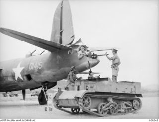 NEW GUINEA, 1942-08-11. THE CREW OF A 39TH INFANTRY BATTALION, AUSTRALIAN MILITARY FORCES, BREN GUN CARRIER PAY A CALL ON THE REAR-GUNNER OF AN AMERICAN US 22ND BOMB GROUP B26 GIANT BOMBER AS IT ..