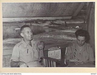 LAE, NEW GUINEA. 1945-05-15. LIEUTENANT W.S. BROWNE, OFFICER- IN- CHARGE VISITORS' SECTION (1), HEADQUARTERS FIRST ARMY, DICTATING A LETTER TO STAFF SERGEANT D. LENTHALL (2), IN CAMP COMMANDANT'S ..