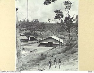 PORT MORESBY, PAPUA, NEW GUINEA, 1944-02-14. THE "9PA" AUSTRALIAN BROADCASTING COMMISSION STATION, WITH ITS 90 FEET AERIAL MASTS NEARING COMPLETION ON THE RIDGE IN THE BACKGROUND