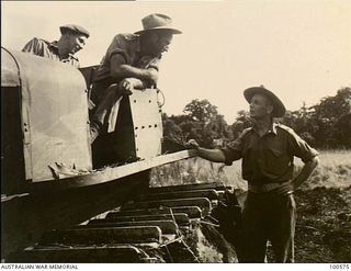 Lae, New Guinea. 1944-07-26. Major M. A. Rankin, Officer Commanding, talking with two of the bulldozer drivers of 2/3rd Forestry Company in the Busu Forest