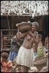 Mortuary ceremony: woman carries basket of food to be shared with participants