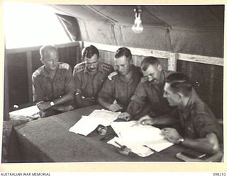 MISSION POINT, NEW GUINEA. 1945-10-24. OFFICERS OF 67 INFANTRY BATTALION (BRITISH COMMONWEALTH OCCUPATION FORCE (BCOF)) DISCUSSING EMBARKATION DETAILS IN THE ADMINISTRATION COMMAND OFFICE. A NEW ..