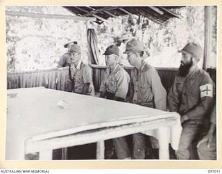 MAJOR GENERAL K. KIJIMA (2), LIEUTENANT COLONEL R. MINOBE, MEDICAL OFFICER (4) AND JAPANESE MEMBERS IN THE RECEPTION HUT AT NUMA NUMA PLANTATION. THEY ARE ATTENDING A DISCUSSION WITH CAPTAIN W. ..