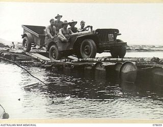MOTUPENA POINT, BOUGAINVILLE ISLAND, 1945-01-26. A JEEP AND TRAILER OF THE 7TH INFANTRY BRIGADE CROSSING A TEMPORARY FLOATING BRIDGE ACROSS THE ADELE RIVER BUILT BY AUSTRALIAN ARMY ENGINEERS BY ..