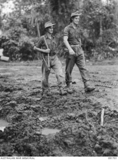 CAPE WOM, WEWAK AREA, NEW GUINEA. 1945-05-06. PRIVATE M. LEMISH (1), WITH SERGEANT A.K. ERBY (2), WALKING ALONG A MUDDY ROAD IN THE AREA