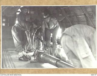 WARD'S DROME, NEW GUINEA. 1943-11-16. TROOPS OF THE 2/5TH AUSTRALIAN FIELD REGIMENT, 7TH AUSTRALIAN DIVISION LOADING THE BARREL OF A LONG 25-POUNDER GUN INTO A DOUGLAS TRANSPORT AIRCRAFT, DURING AN ..