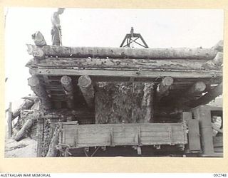 WEWAK AREA, NEW GUINEA. 1945-05-30. SAPPER H.J. INMAN, 2/8 FIELD COMPANY ROYAL AUSTRALIAN ENGINEERS (1), CHECKING A LOAD OF CORAL AFTER IT HAD BEEN TIPPED INTO A TRUCK FOR THE NEW MAPRIK ROAD (BIG ..