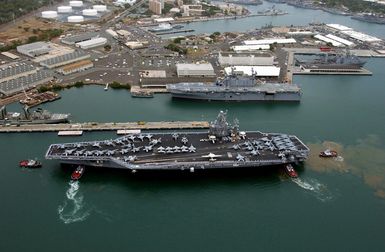 Several tugboats assist the US Navy (USN) Nimitz class Aircraft Carrier USS JOHN C. STENNIS (CVN 74) to the Navy Supply Depot pier during a port call to the Pearl Harbor Naval Shipyard, Hawaii (HI). The USN Amphibious Assault Ship USS TARAWA (LHA 1) is immediately in the background and a USN Whidbey Island LSD 41 Class Dock Landing Ship is in the next pier. The STENNIS is visiting Pearl Harbor to take part in Rim of the Pacific (AC) 2004. AC is the largest international maritime exercise in the waters around the Hawaiian Islands. This years exercise includes seven participating nations: Australia, Canada, Chile, Japan, South Korea, the United Kingdom and the United States....