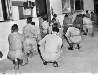 PORT MORESBY, PAPUA, 1944-02-20. AMERICAN AND AUSTRALIAN SERVICEMEN AT WORSHIP IN AN OVERFLOWING CONGREGATION AT AN ENTRANCE TO THE ROMAN CATHOLIC CHURCH