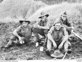 RAMU VALLEY, NEW GUINEA, 1944-02-29. MEMBERS OF THE NO.16 AND NO.17 PLATOON, "D" COMPANY, 2/12TH INFANTRY BATTALION, RELAX OVER A CUP OF TEA AT KESAWAI. IDENTIFIED PERSONNEL ARE: QX18328 CORPORAL ..