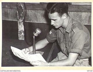 CAPE WOM, NEW GUINEA. 1945-09-29. CORPORAL C.C. CHAPLIN AT RADIO 6 DIVISION, HEADQUARTERS 6 DIVISION, READING OUT THE LOCAL NEWS AFTER THE REBROADCAST OF THE NATIONAL NEWS. THE STATION REOPENED ON ..