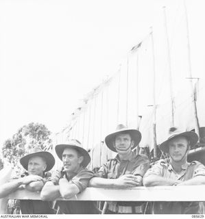 HERBERTON RACECOURSE, WONDECLA, ATHERTON TABLELAND, QLD. 1945-01-19. SPECTATORS AT HQ 9 DIVISION VIEWING THE 9 DIVISION GYMKHANA FROM THE STANDS WITH UNIT FLAGS FLYING IN THE BACKGROUND. IDENTIFIED ..