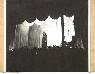 ELA BEACH, NEW GUINEA. 1943-12-21. MISS KITTY BLUETT OF THE GLADYS MONCRIEFF CONCERT PARTY SINGING TO THE TROOPS AT A CONCERT HELD ON THE ELA BEACH SPORTS GROUND