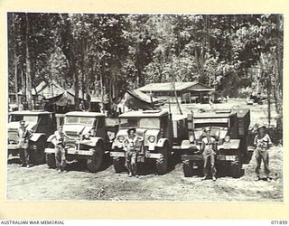 LAE, NEW GUINEA. 1944-03-30. THE TRANSPORT PLATOON AREA AT THE 151ST GENERAL TRANSPORT COMPANY SHOWING TRUCKS IN LINE WITH THE MESS AND OTHER QUARTERS AT THE BACKGROUND. LEFT TO RIGHT: V235686 ..