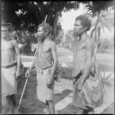 Policeman with two bush men, one holding a staff and the other carrying a bag, Salamaua, New Guinea, 1937 / Sarah Chinnery