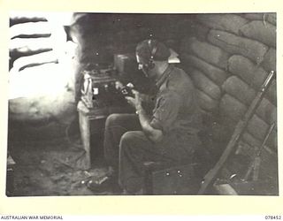 MOTUPINA POINT AREA, BOUGAINVILLE ISLAND. 1945-01-20. VX77855 GUNNER J.G. WEST, 2ND FIELD REGIMENT, OPERATING A NO.11 WIRELESS SET DURING OPERATIONS AGAINST THE JAPANESE IN THE AREA. THIS SET IS ..