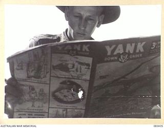 AT SEA, NEW GUINEA AREA, 1944-11-12. CORPORAL K. BRADFORD, 6 DIVISION PROVOST COMPANY, READS "YANK DOWN UNDER" WHILE RELAXING ABOARD USS MEXICO DURING MOVEMENT TO AN OPERATIONAL AREA