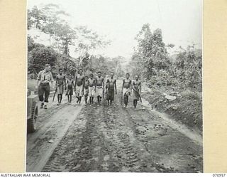 ZENAG, NEW GUINEA. 1944-02-27. NX76577 CAPTAIN N.F. HATCHER (1), OF NO. 4 PLATOON, 2/1ST MECHANICAL EQUIPMENT COMPANY, ROYAL AUSTRALIAN ENGINEERS, WITH NATIVE WORKERS 53 MILES FROM WAU. THIS WIDE ..