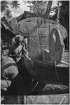 Canoe-building: carved washboard and traverse prowboard on a fishing canoe, man carves side of canoe