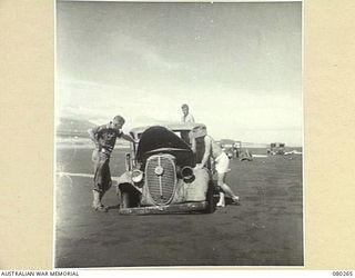 HANSA BAY, NEW GUINEA. 1944-07-10. A JAPANESE CHEVROLET STAFF VEHICLE UNDER SALVAGE BY THE 5TH DIVISION SALVAGE GROUP. BOGGED JAPANESE LORRIES STAND IN THE BACKGROUND