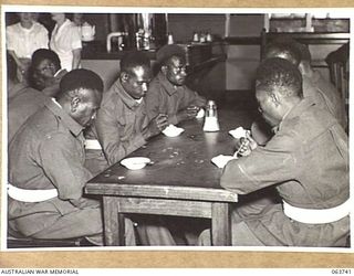 ALEXANDRIA, NSW. 1944-01-24. AUSTRALIAN AND NEW GUINEA ADMINISTRATION UNIT NATIVES ENJOYING AN ICE CREAM IN THE FACTORY CANTEEN DURING THEIR TOUR OF SLAZENGER'S FACTORY