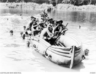 Henry Reid Bay, Bougainville, Solomon Islands. 1945-03. Australian troops in pursuit of the Japanese, using an inflatable assault boat captured from the enemy, to cross a stream
