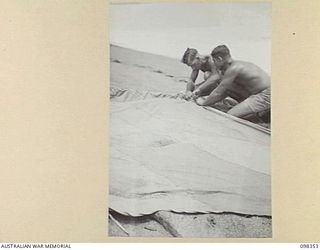 WEWAK, NEW GUINEA. 1945-10-28. PRIVATE V.R. JOBSON (1) AND SERGEANT R.E. HIGGINS (2), MEMBERS OF 16 INFANTRY BRIGADE, MENDING THE SAIL ON THE MAST OF THEIR SKIFF, AN ENTRY IN THE WEWAK REGATTA TO ..