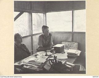 MAPRIK, NEW GUINEA. 1945-10-03. CAPTAIN G. NEILSON, COMMANDING OFFICER AUSTRALIAN NEW GUINEA ADMINISTRATIVE UNIT HEADQUARTERS, AND LIEUTENANT G. MORRIS CONDUCTING A COURT TO TRY A NATIVE WHO HAS ..