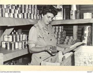 LAE AREA, NEW GUINEA. 1944-11-06. WARRANT OFFICER II, E.C. COLLINS, WHO IS RESPONSIBLE FOR SPECIAL DIETS AT 2/7 GENERAL HOSPITAL, SELECTS TINNED FOOD FOR INDIVIDUAL CASES