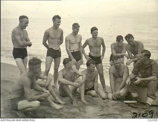 TOROKINA, BOUGAINVILLE ISLAND, SOLOMON ISLANDS. 1945-01-19. FLIGHT LIEUTENANT J. W. HENDERSON, RAAF CHAPLAIN (EXTREME RIGHT), TAKES AN OPPORTUNITY OF HAVING AN INFORMAL CHAT ON THE BEACH