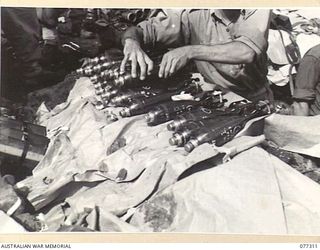 TOROKINA AREA, BOUGAINVILLE ISLAND. 1944-11-29. N451257 PRIVATE G.D. PATTERSON, 9TH INFANTRY BATTALION, STACKING 3" MORTAR BOMBS TO BE USED IN THE ATTACK ON LITTLE GEORGE HILL