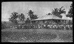 Hookworm lecture to large group in front of a building