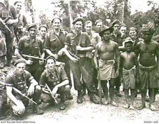 THE SOLOMON ISLANDS, 1945-03-27. A GROUP OF SOLDIERS WITH SOME NATIVES ON BOUGAINVILLE ISLAND. (RNZAF OFFICIAL PHOTOGRAPH.)