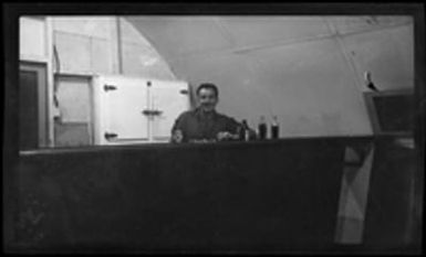 [Serviceman seated a bar in Quonset hut]