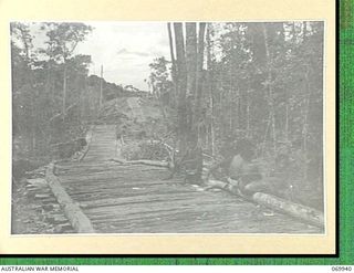 MILNE BAY, NEW GUINEA. 1943-03. NATIVE BOYS HAVING A MEAL ALONGSIDE THE HILL STATION ROAD. THIS SECTION IS BEING REBUILT AS A CORDUROY ROAD BY SAPPERS OF "D" COMPANY, 2/1ST PIONEER BATTALION AND ..