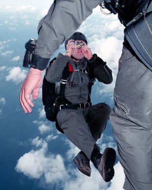 A US Navy (USN) Sailor assigned to Naval Special Warfare Unit One (NSWU1), takes a picture of the other jumpers exiting the ramp of helicopter during a High Altitude Low Opening (HALO) jump over Orote Point, Santa Rita, Guam