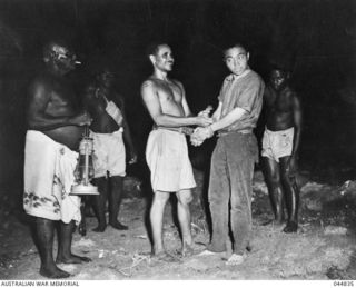 NEW GEORGIA, SOLOMON ISLANDS. 1943-02. NATIVE SCOUTS OF KENNEDY'S GROUP BRING IN A 19 YEAR OLD CAPTURED JAPANESE PILOT TO THE SEGI STATION COMMANDED BY CAPTAIN D.G. KENNEDY, BRITISH SOLOMON ISLANDS ..