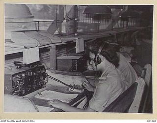 LAE, NEW GUINEA, 1945-05-16. SIGNALWOMAN N. HUMPHRIES, WIRELESS OPERATOR (1), WORKING IN THE WIRELESS ROOM, SIGNALS, HEADQUARTERS FIRST ARMY. AUSTRALIAN WOMEN'S ARMY SERVICE PERSONNEL ARE TAKING ..