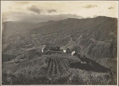 Scenes at Ononge [Looking down to a collection of buildings and a church overlooking a valley] Frank Hurley