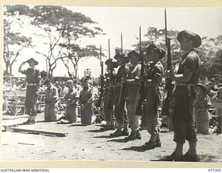 MADANG, NEW GUINEA. 1944-10-29. AN AUSTRALIAN ARMY GUARD PRESENTING ARMS DURING THE SOLEMN HIGH MASS CELEBRATED ON THE LOCAL SPORTS OVAL