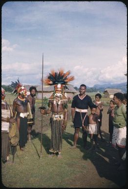 A man in full bilas (decoration), front view, being admired by station police : Wahgi Valley, Papua New Guinea, 1954-1955 / Terence and Margaret Spencer