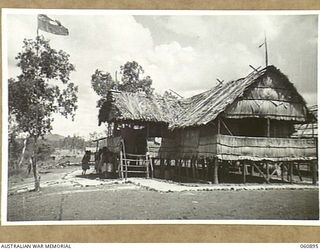PA PA, PAPUA. 1943-12-02. PATROL OFFICERS RESIDENCE AND POLICE POST. IN FRONT OF THE HUT NATIVE WOMEN CAN BE SEEN LISTENING TO AN INVESTIGATION BEING CONDUCTED INSIDE