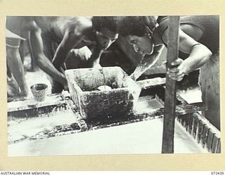 KOKODA, NEW GUINEA. 1944-04-13. NATIVE ORGANISED BY THE SUB DISTRICT OFFICE, AUSTRALIAN NEW GUINEA ADMINISTRATIVE UNIT, CHECKING THE SPECIFIC GRAVITY OF THE WATER AND LATEX MIXTURE BEFORE THE ..