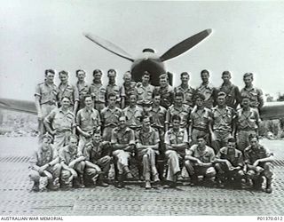 Group portrait of the Commanding Officer and pilots of No 77 Squadron RAAF, in front of one of the Curtiss P-40E Kittyhawk fighter aircraft with which the squadron was equipped. Identified, back ..