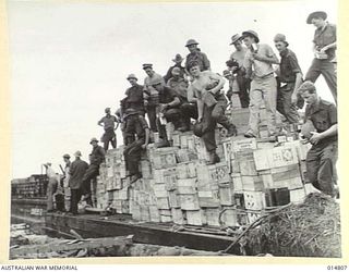 1943-05-07. NEW GUINEA. MILNE BAY. AN ALLIED VESSEL WAS HIT DURING THE 1943-04-14, JAPANESE RAID ON MILNE BAY. BARGES WITH STORES FROM THE DAMAGED SHIP BEING BROUGHT TO LAND. (NEGATIVE BY N. BROWN)