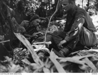 BOUGAINVILLE ISLAND, 1945-01-21. NX76537 MAJOR B. SHORT, REGIMENTAL MEDICAL OFFICER (3) ASSISTED BY QX62698 PRIVATE H.G.A. MACDONALD, MEDICAL ORDERLY (1) TREATING Q272652 PRIVATE R.G. MERRIT AT THE ..