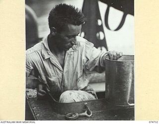 MADANG, NEW GUINEA. 1944. THE ENGINEER OF THE 593RD UNITED STATES BARGE COMPANY'S COURIER BARGE EMERGING ON DECK FROM THE ENGINE ROOM HATCH JUST BEFORE LEAVING FOR THE TRIP TO ALEXISHAFEN