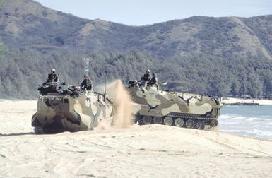 Two AAVP-7 assault amphibian vehicles (AAVs) churn up a sand as they move onto the beach after leaving a Navy ship during Exercise RimPac '88. The AAVs are originally from Marine Corps Base, 29 Palms, California